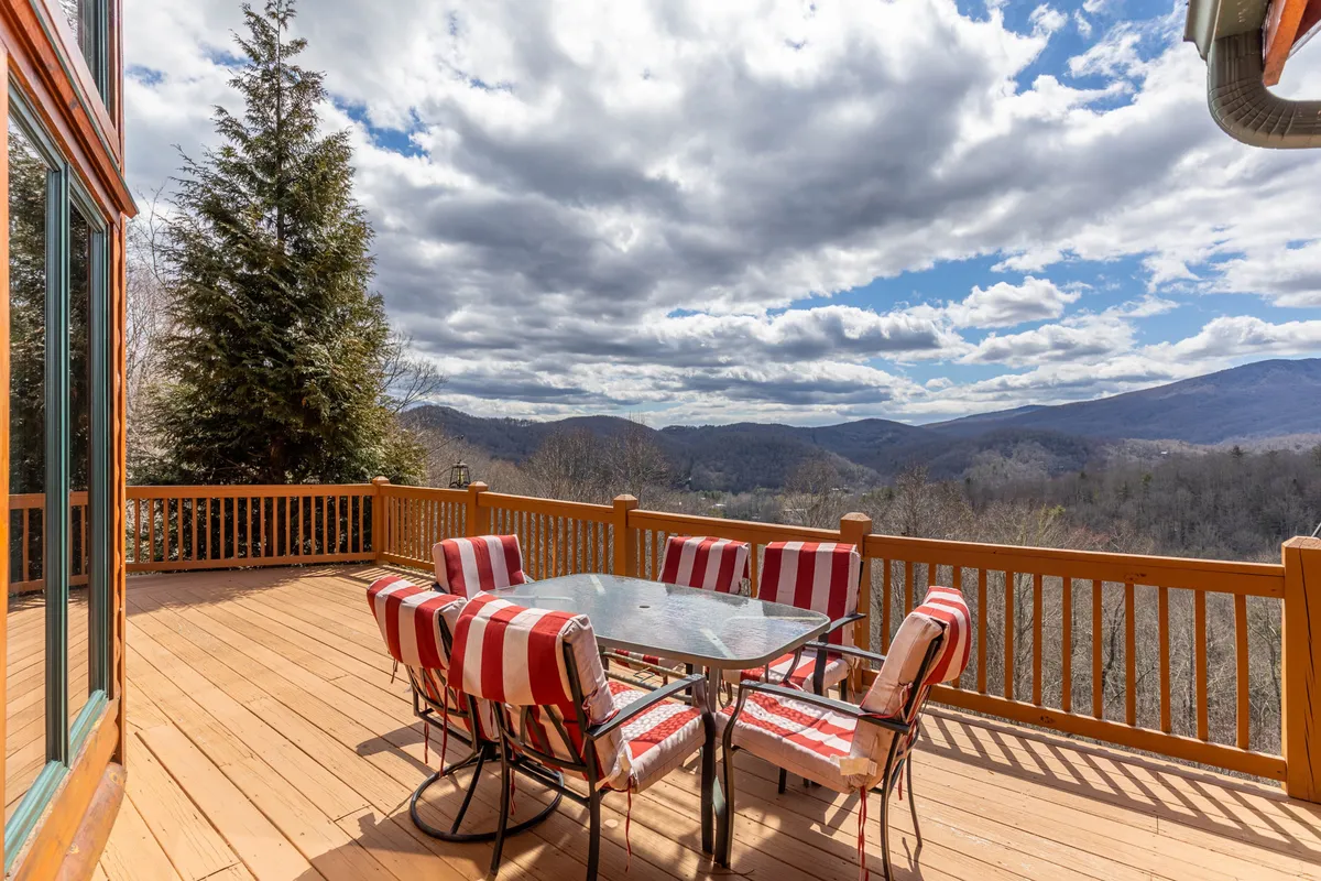 A table is set for dining on a deck, surrounded by striped chairs and framed by a stunning mountain vista. The setup is ideal for al fresco meals, from sunrise breakfasts to sunset dinners, offering a seamless blend of nature and comfort.