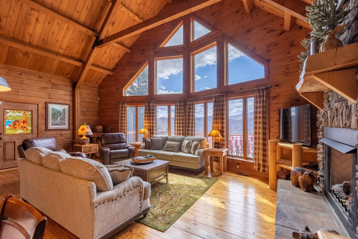A spacious interior view spotlighting comfortable seating, a prominent stone fireplace, and expansive windows that invite in mountain vistas. The room’s arrangement encourages togetherness, whether for games, reading, or simply enjoying the view.